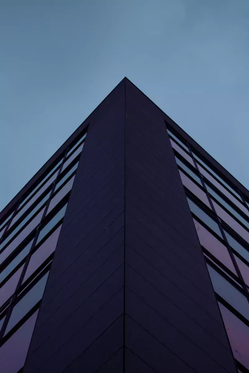 Aufwärtsstrebende Kante eines modernen Gebäudes vor blau-violettem Dämmerungshimmel